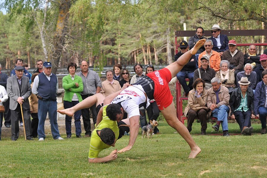 Combate de lucha leonesa al aire libre con público reunido alrededor