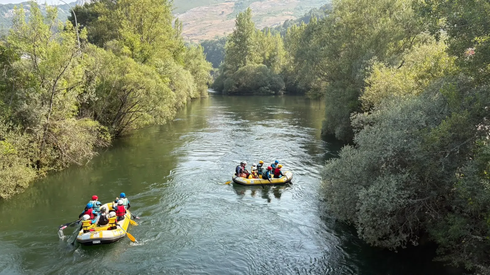 Dos balsas amarillas descienden por el Esla entre árboles de ribera.